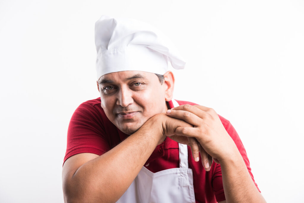 Portrait of handsome Indian male chef posing while doing activities
